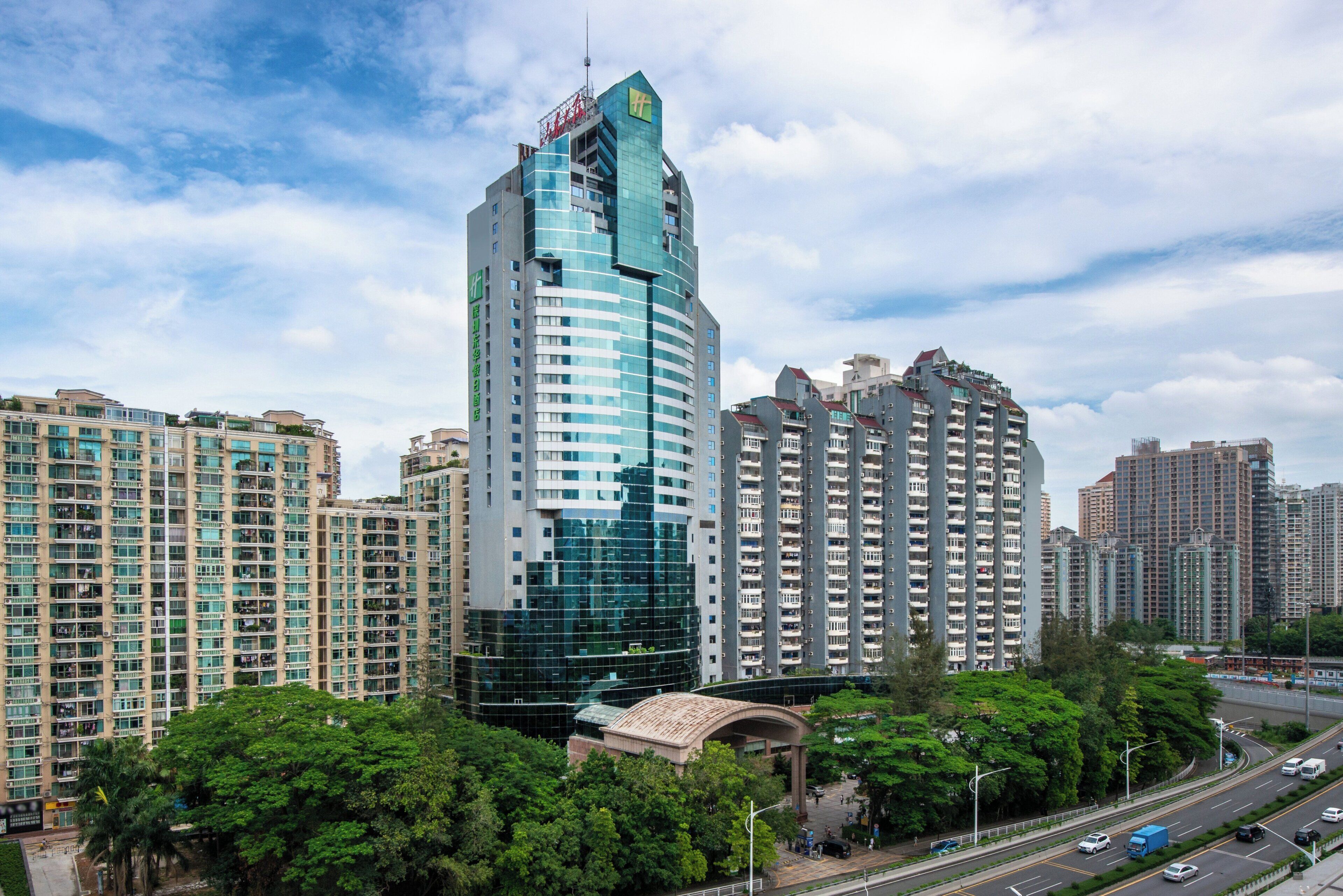 A high-rise building with a distinctive curved glass facade, surrounded by other residential high-rises.