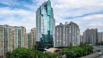 A high-rise building with a distinctive curved glass facade, surrounded by other residential high-rises.