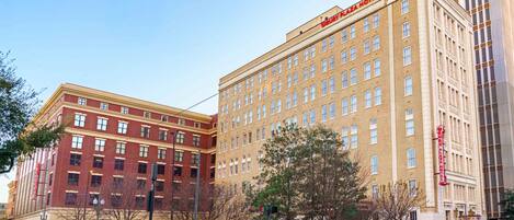 A multi-story hotel with a prominent sign, a street intersection, and a clear sky.