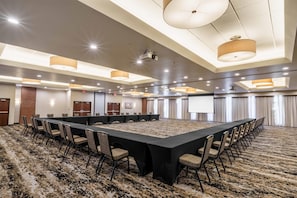 A conference room with a long table, chairs, and a carpeted floor.