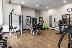 A gym with various exercise equipment, a clock on the wall, and a green exercise ball. - Drury Plaza Hotel New Orleans (New Orleans)