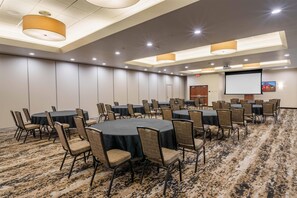 A conference room with round tables and chairs, a projector screen, and a carpeted floor. - Drury Plaza Hotel New Orleans (New Orleans)