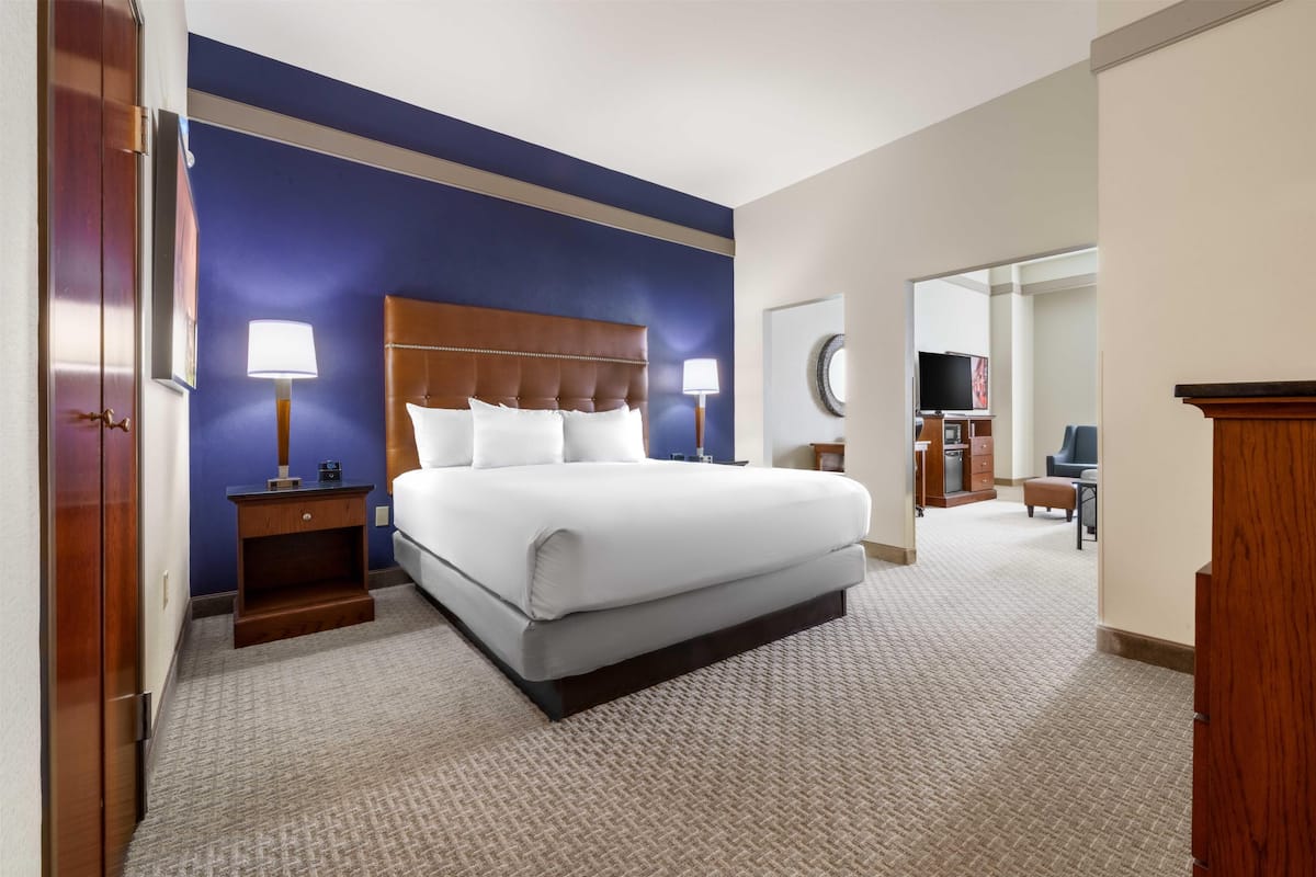 A hotel room with a large bed, bedside tables, a mirror, and a television in the corner.