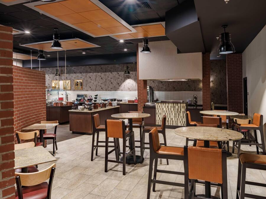 Un restaurante con varias mesas y sillas, una zona de cocina y una pared de ladrillo.