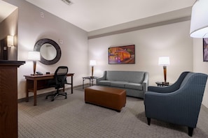 A hotel room with a desk, office chair, sofa, ottoman, and two lamps. - Drury Plaza Hotel New Orleans (New Orleans)