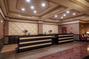 A hotel reception area with a reception desk, a waiting area, and a door to the rooms. - Drury Plaza Hotel New Orleans (New Orleans)