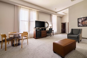 A hotel room with a dining table, chairs, a television, a desk with a computer, a sofa, and a large window with curtains. - Drury Plaza Hotel New Orleans (New Orleans)
