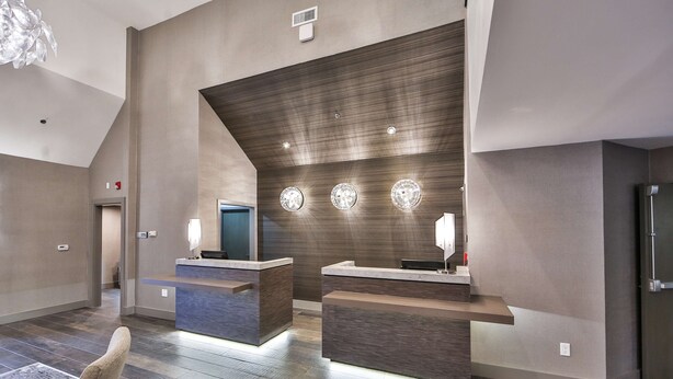 Un espace d’accueil moderne doté de deux comptoirs, d’un grand lustre et d’un plafond haut.