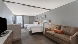 A hotel room with a bed, a sofa, a desk, and a TV. - Hilton Garden Inn Philadelphia Center City (Philadelphia)