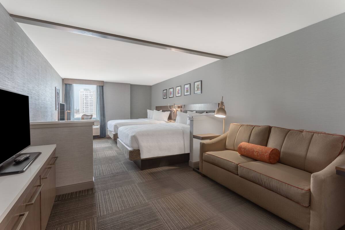 A hotel room with a bed, a sofa, a desk, and a TV.