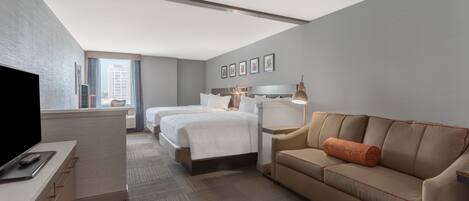 A hotel room with a bed, a sofa, a desk, and a TV.