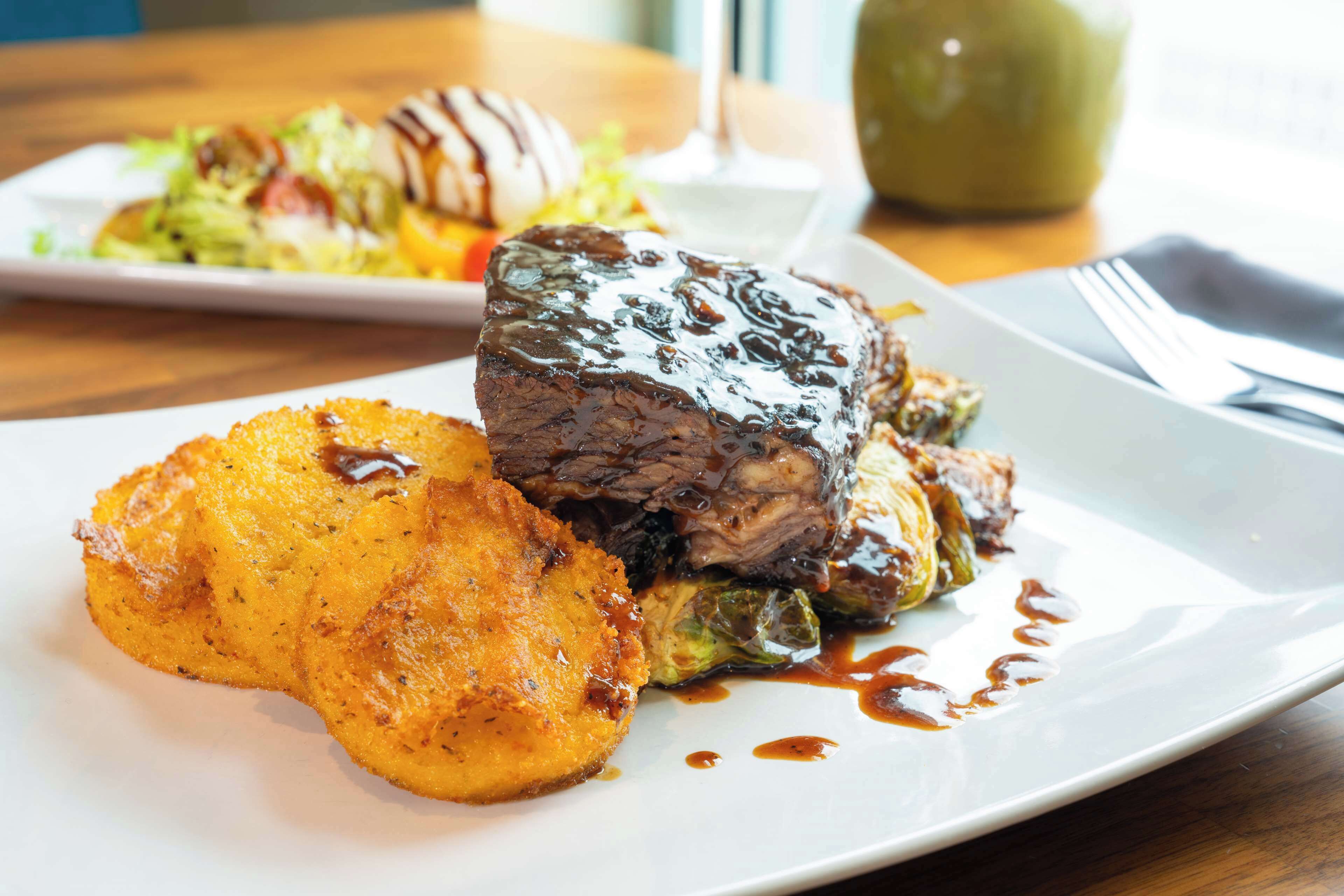 A plate of food with a beef steak, roasted potatoes, and Brussels sprouts.