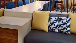 Een moderne hotellobby met een ruime zithoek, een receptiebalie en een trap.