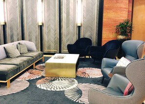 A modern lounge area with a sofa, chairs, a coffee table, and patterned rugs. - Amora Hotel Jamison Sydney (Sydney)