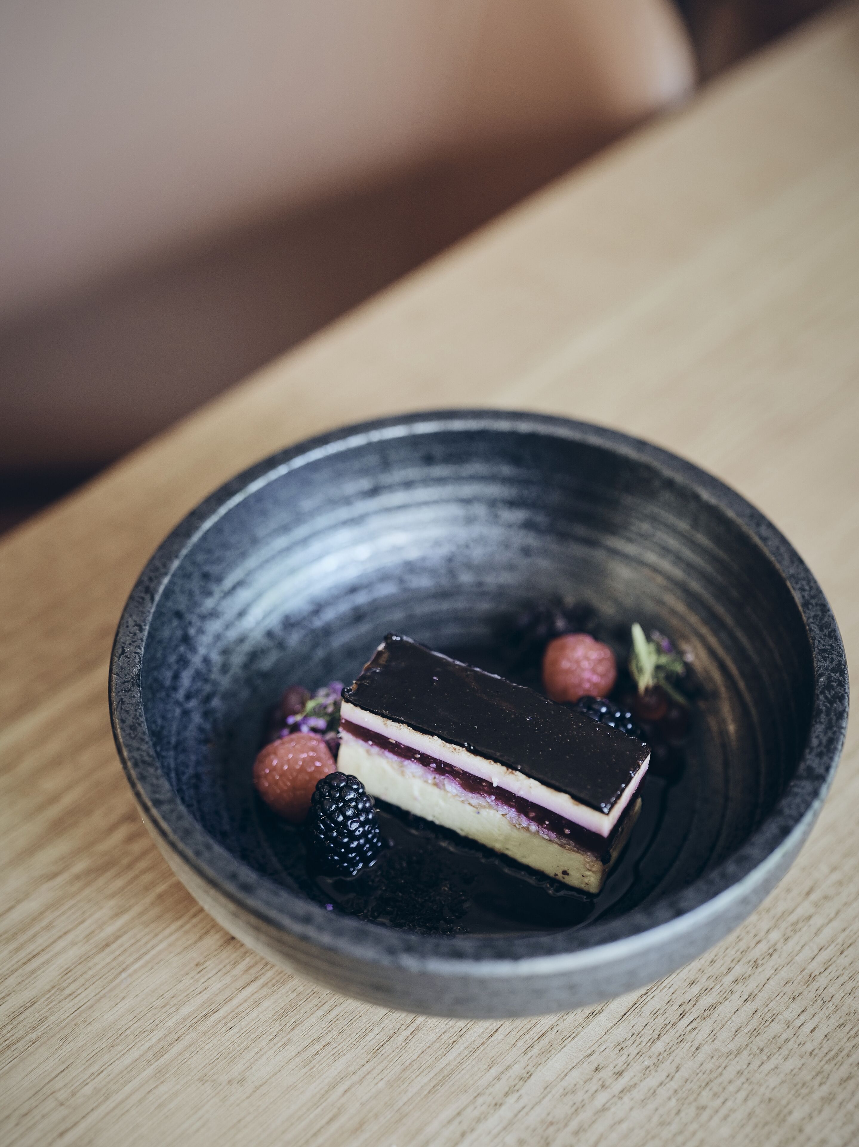 A dessert in a bowl with berries and a slice of cake.