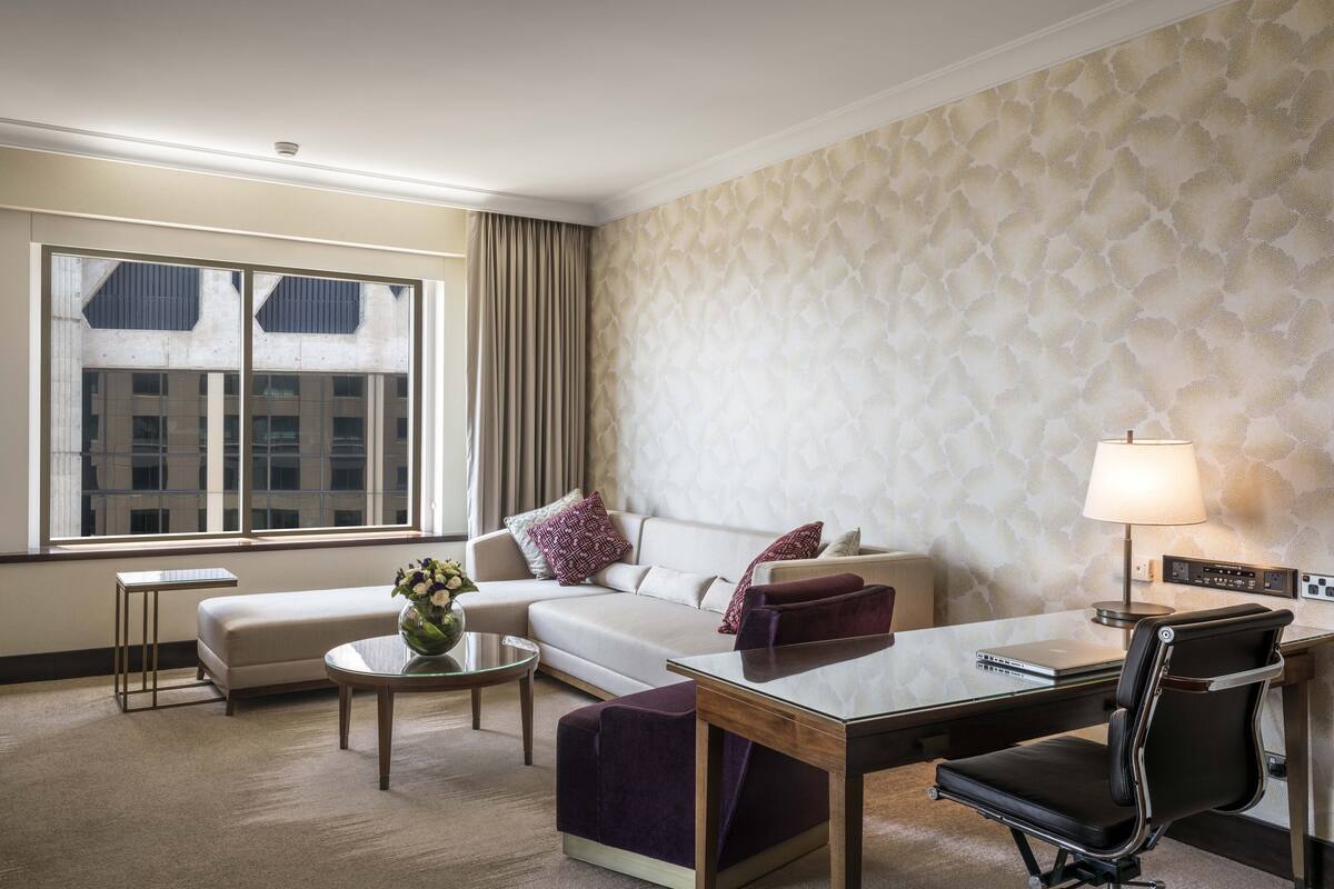 Ett hotellrum med en soffa, ett skrivbord, en stol, ett soffbord och en lampa.
