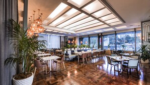 Un restaurante espacioso con suelo de madera, ventanas amplias e iluminación colgante moderna.