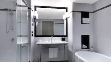 Un baño moderno con ducha envuelta en cristal, un lavabo blanco con espejo y una bañera independiente.