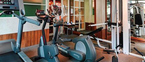 A gym with cardio equipment, weight machines, and a mirror.