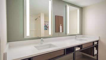 A modern bathroom with a double sink vanity, a large mirror, and built-in shelves for towels.