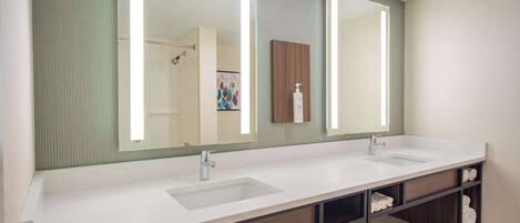 A modern bathroom with a double sink vanity, a large mirror, and built-in shelves for towels.