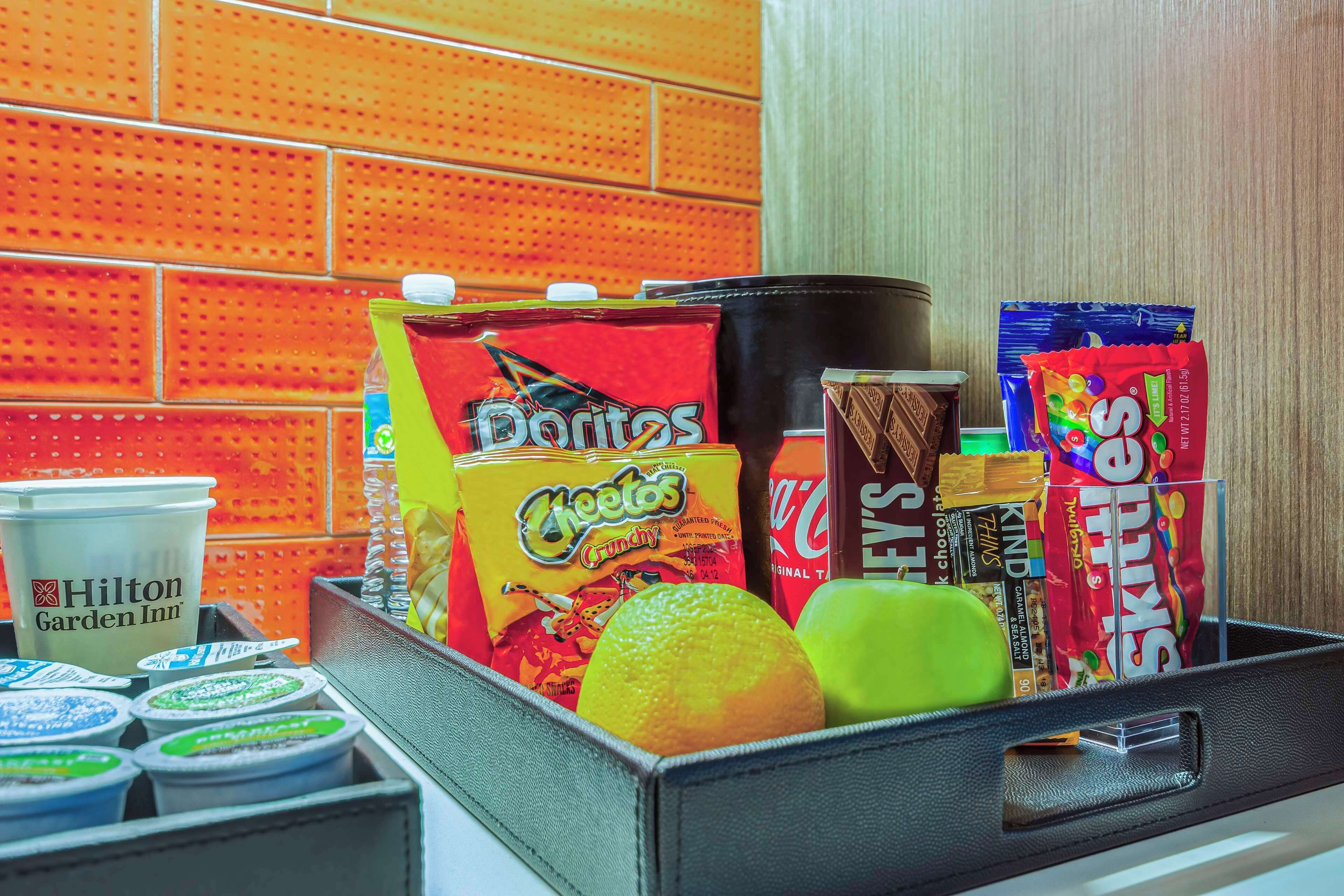 Tarjottimella on erilaisia pikkupurtavia, kuten Hilton Garden Inn -hotellin mukin, Cheetos-sipsien, Coca-Colan, Hershey’s-suklaan ja Skittles-karkkien.