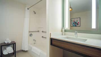 Un baño moderno con ducha, lavabo con espejo y un perchero para toallas.