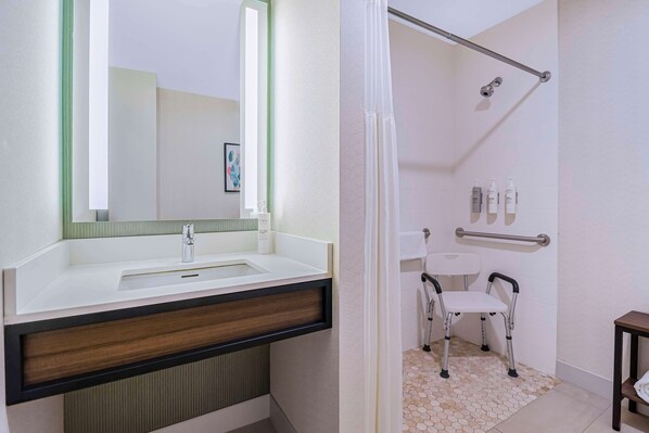A bathroom with a white sink, mirror, and shower area.