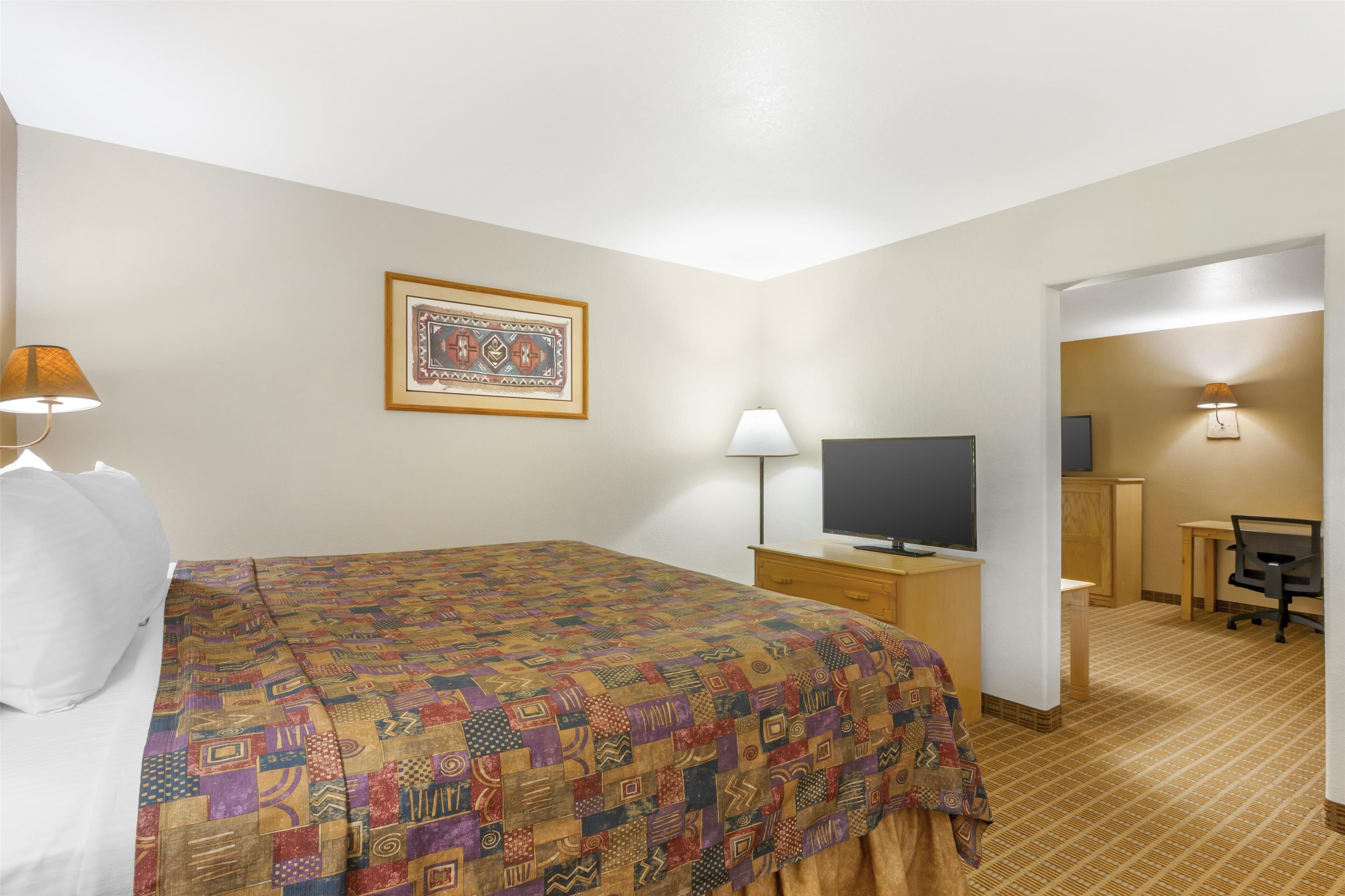 A hotel room with a bed, a desk, a television, and a chair.