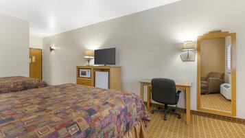 A hotel room with two beds, a desk with a computer, a TV, a mirror, and a lamp.