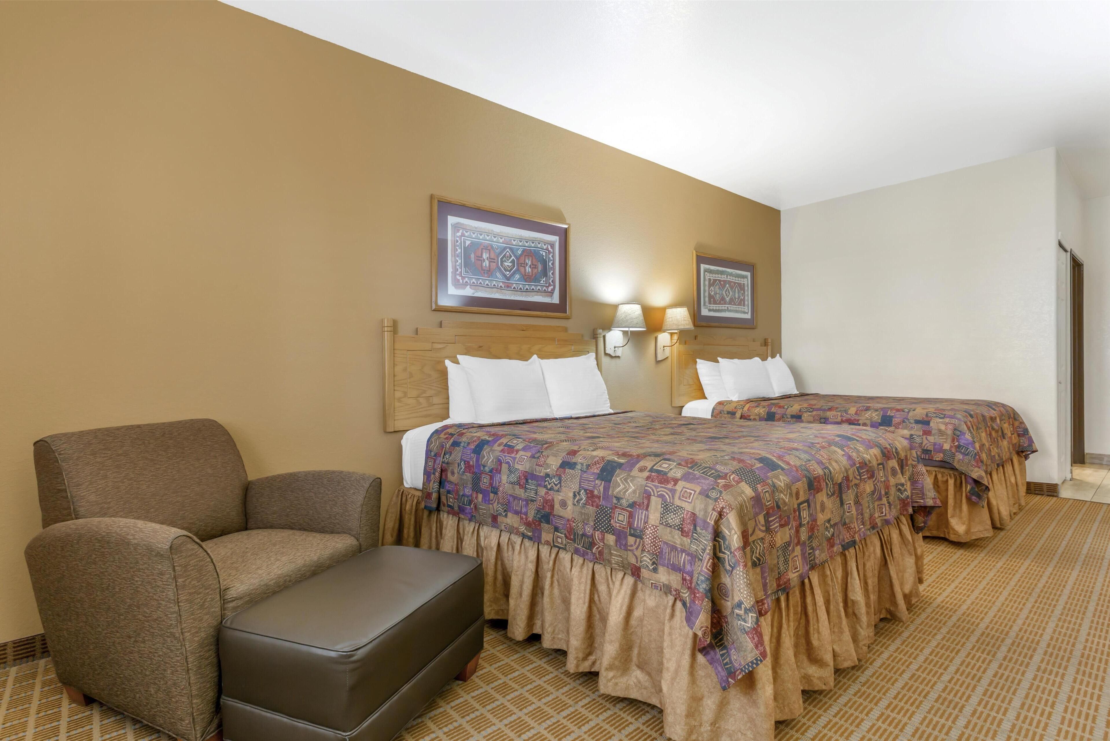 A hotel room with two beds, a sofa, and a small table.