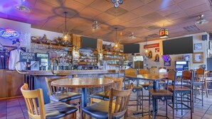 A bar area with wooden tables and chairs, a beer tap, and various bottles and glasses on shelves. - Best Western Gold Canyon Inn & Suites (Gold Canyon)