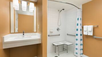 A bathroom with a white sink, mirror, and shower.