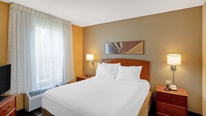 A hotel room with a large bed, two bedside tables with lamps, a flat-screen TV, and a window with curtains. - MainStay Suites Mt. Laurel - Philadelphia (Mount Laurel)
