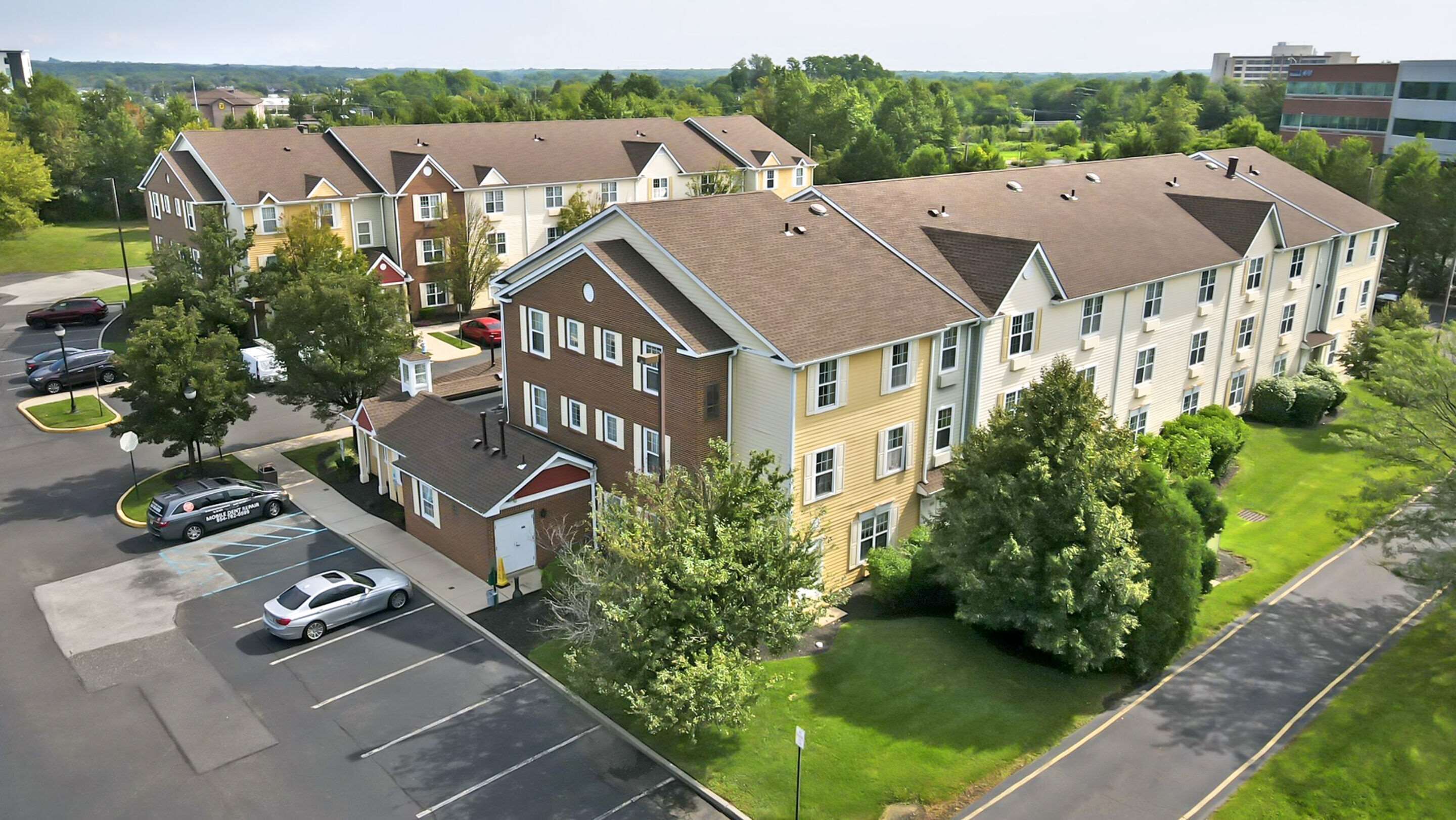 A multi-story residential building with a parking lot and green lawns.