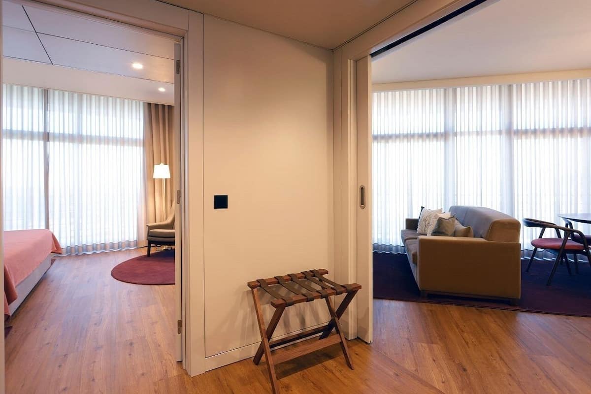 Hotellihuone, jossa on sänky, tuoli, pieni pöytä, sohva ja ruokapöytä.