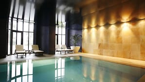 An indoor swimming pool with clear water, surrounded by lounge chairs and a potted plant. - Montebelo Viseu Congress Hotel & Spa (Viseu)