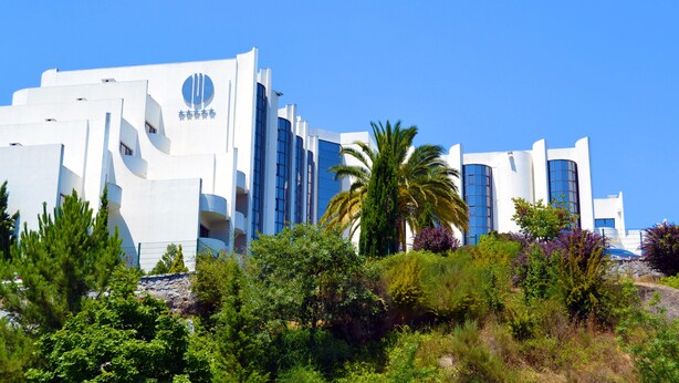 A modern building with a distinctive circular logo and a series of balconies. - Montebelo Viseu Congress Hotel & Spa (Viseu)