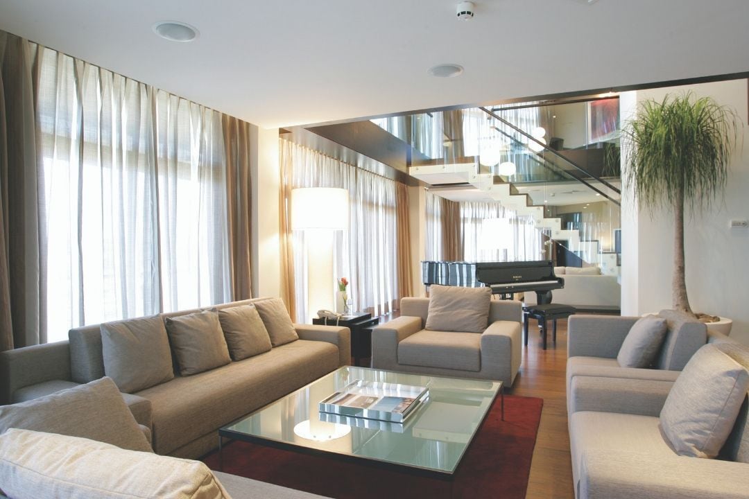 Un salon moderne comprenant un canapé, des fauteuils, une table basse et un piano.
