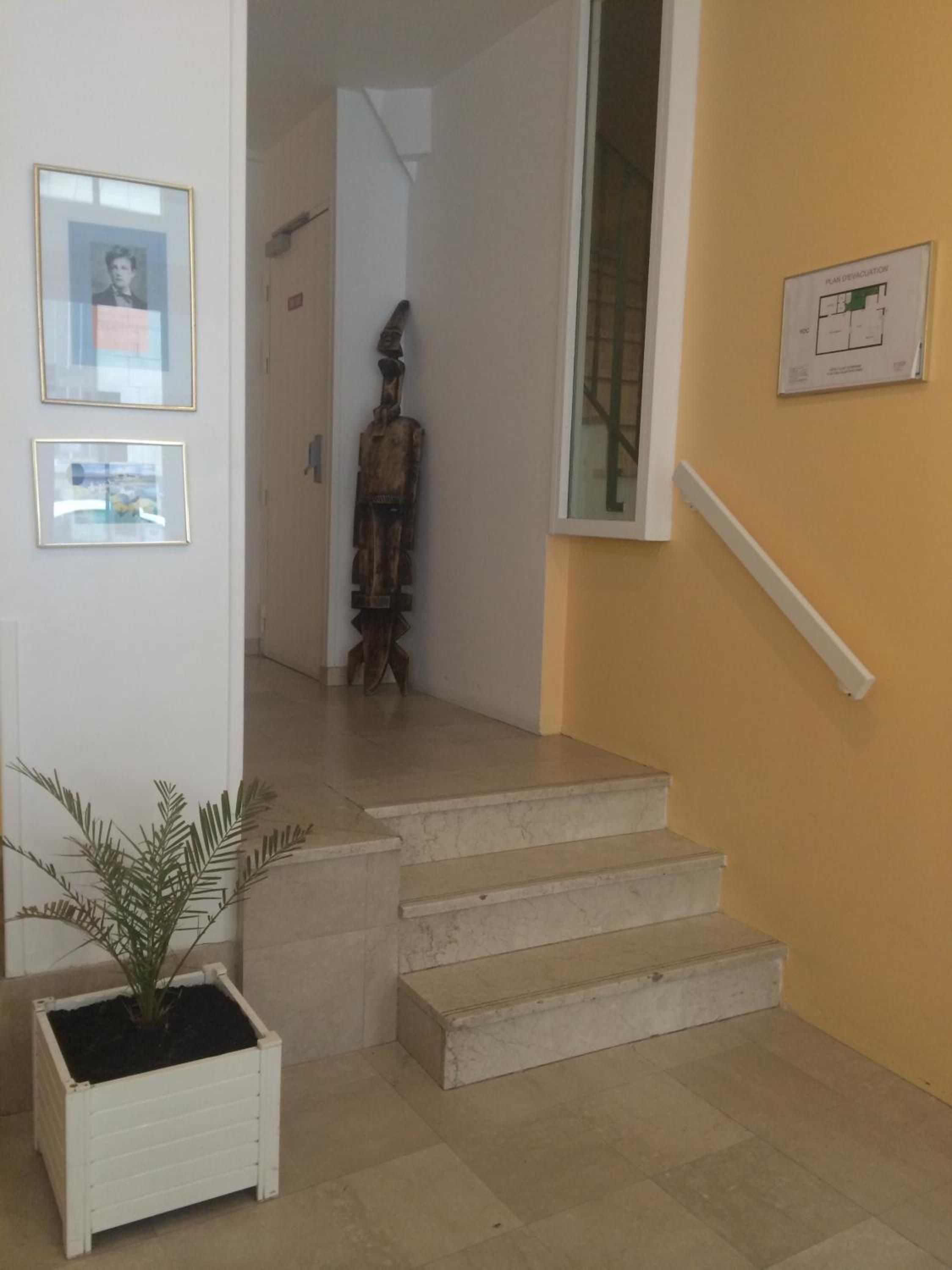 Una escalera que conduce a un segundo piso, con una planta en maceta en la barandilla.