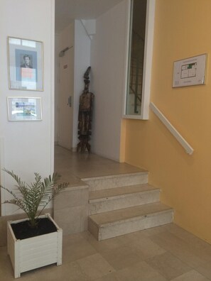 Eine Treppe führt zu einer zweiten Etage, auf der Zwischenebene steht ein Blumentopf.