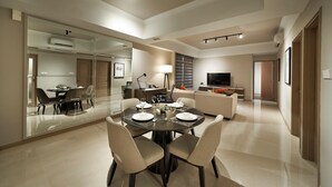 A modern living room with a dining area, a sofa, a TV, and a large mirror. - Great World Residences (Singapore)