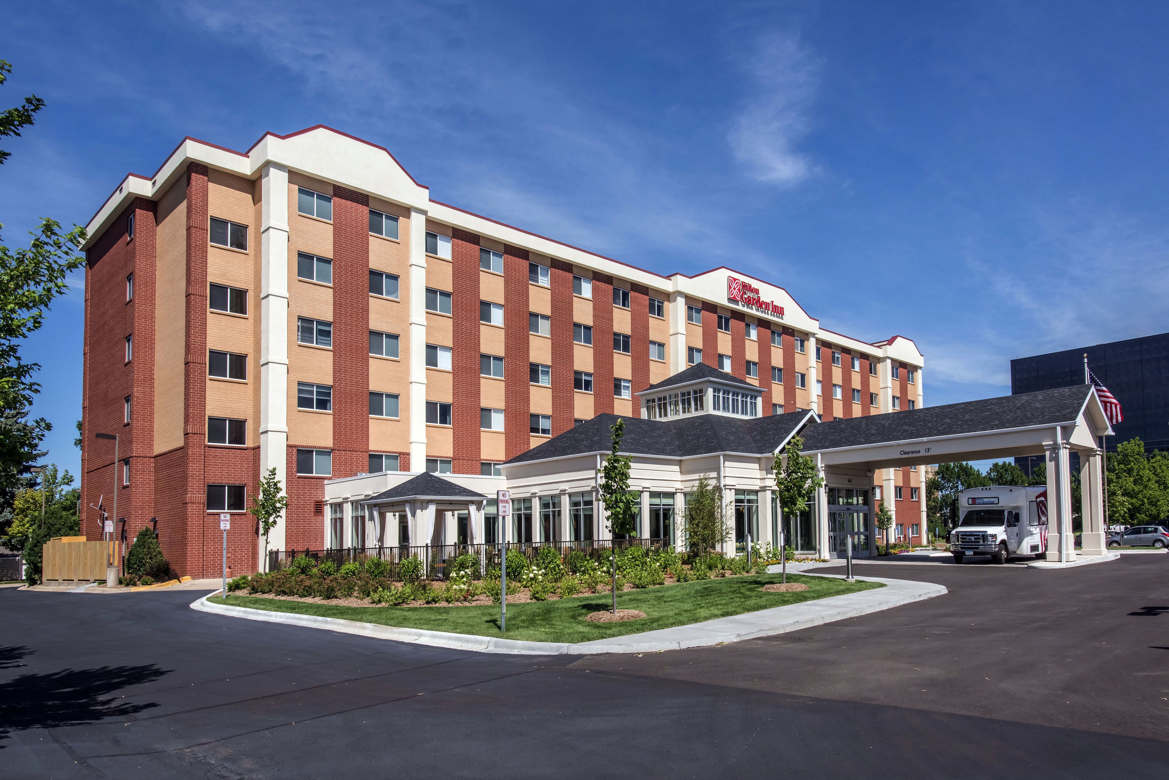 A hotel with a brick facade, a covered entrance, and a parking area.