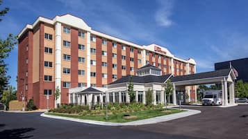 A hotel with a brick facade, a covered entrance, and a parking area.