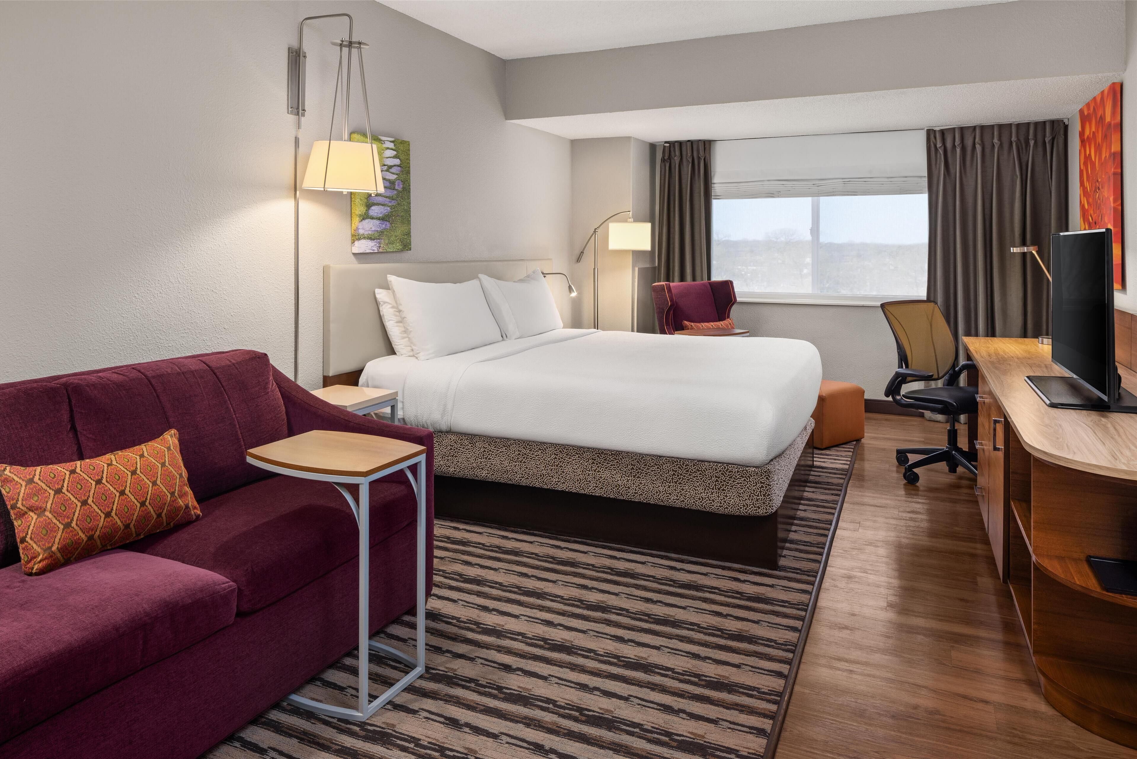 Een hotelkamer met een bed, een bureau, een stoel, een bank en een televisie.