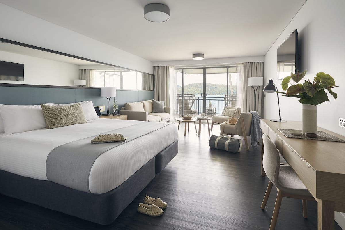 Una habitación de hotel moderna con una cama grande, un escritorio y un balcón con vistas.