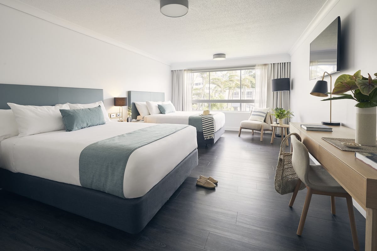 Una habitación de hotel moderna con una cama grande, un escritorio y una silla.