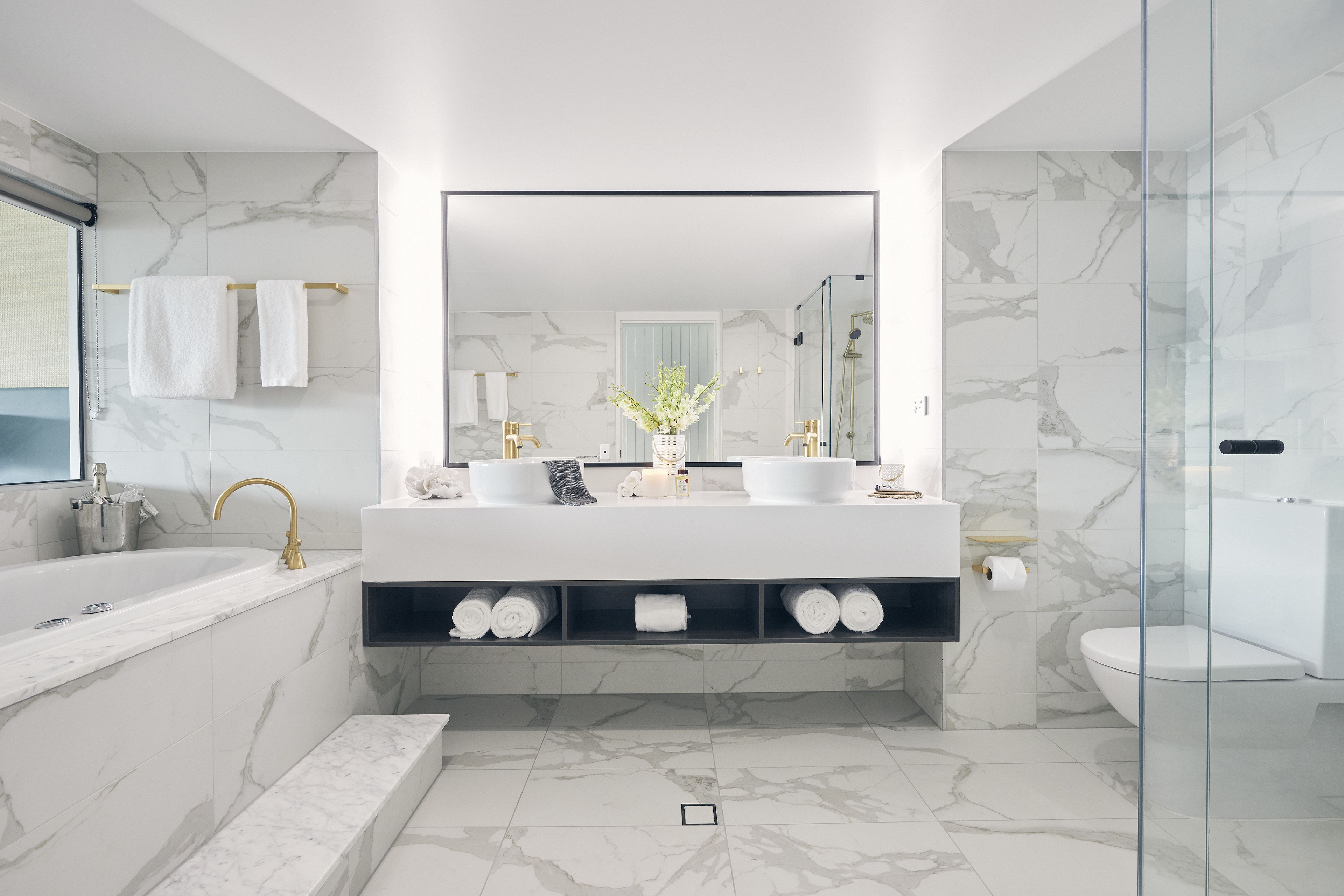 Un baño moderno con un espejo grande, dos lavamanos, una bañera y una zona de ducha.