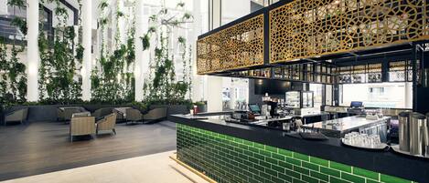 Una zona de bar moderna con un mostrador de azulejos verdes, asientos con sillas acolchadas y un panel decorativo de madera.