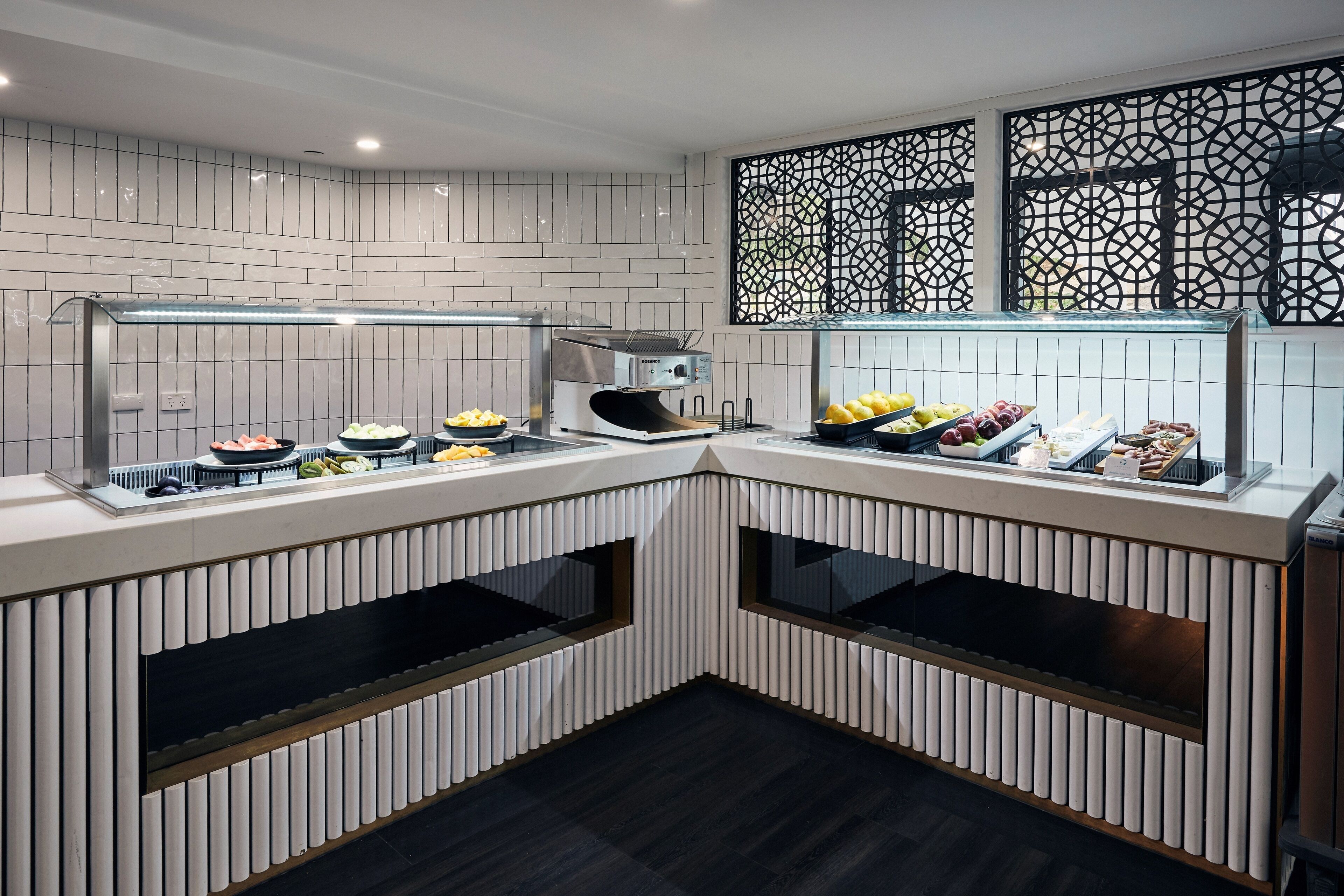 Een moderne keuken met witte betegelde wanden, een inbouwfornuis en diverse etenswaren op het aanrecht.